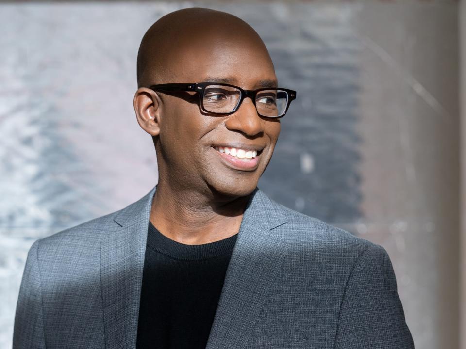 Stacy Spikes smiling in a grey suit with black undershirt