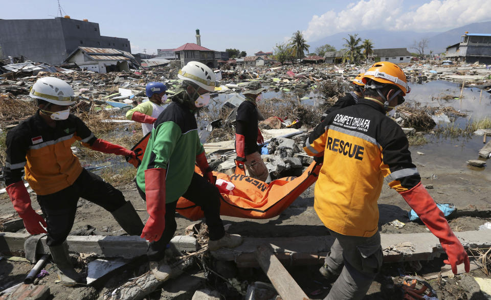 An Indonesian rescue team carries the body of a victim following an earthquake and tsunami in Palu, Central Sulawesi, Indonesia, Wednesday, Oct. 3, 2018. Aid was slowly making its way into areas devastated by the earthquake and tsunami that struck a central Indonesian island, with one neighborhood's residents clapping, cheering and high-fiving in their excitement Wednesday at seeing a stopped truck laden with supplies. (AP Photo/Tatan Syuflana)