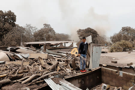 Brian Rivera, who lost 13 members of his family during the eruption of the Fuego volcano, holds his sister's guitar near debris of his home at San Miguel Los Lotes, Escuintla, Guatemala 7 June, 2018. REUTERS/Carlos Jasso