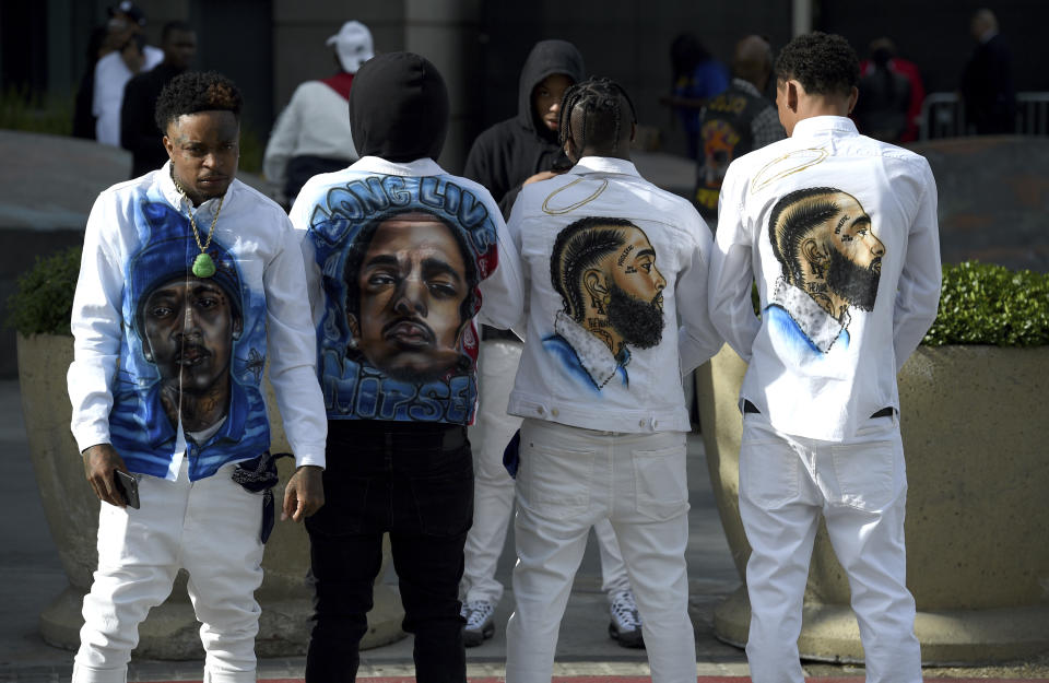 Slum Baby, from left, Yhung To, Lil Cadi PGE and Lo, from the Crenshaw neighborhood of Los Angeles, wear clothing in honor of Nipsey Hussle, whose given name was Ermias Asghedom, at the late rapper's Celebration of Life memorial service on Thursday, April 11, 2019, at the Staples Center in Los Angeles. (Photo by Chris Pizzello/Invision/AP)