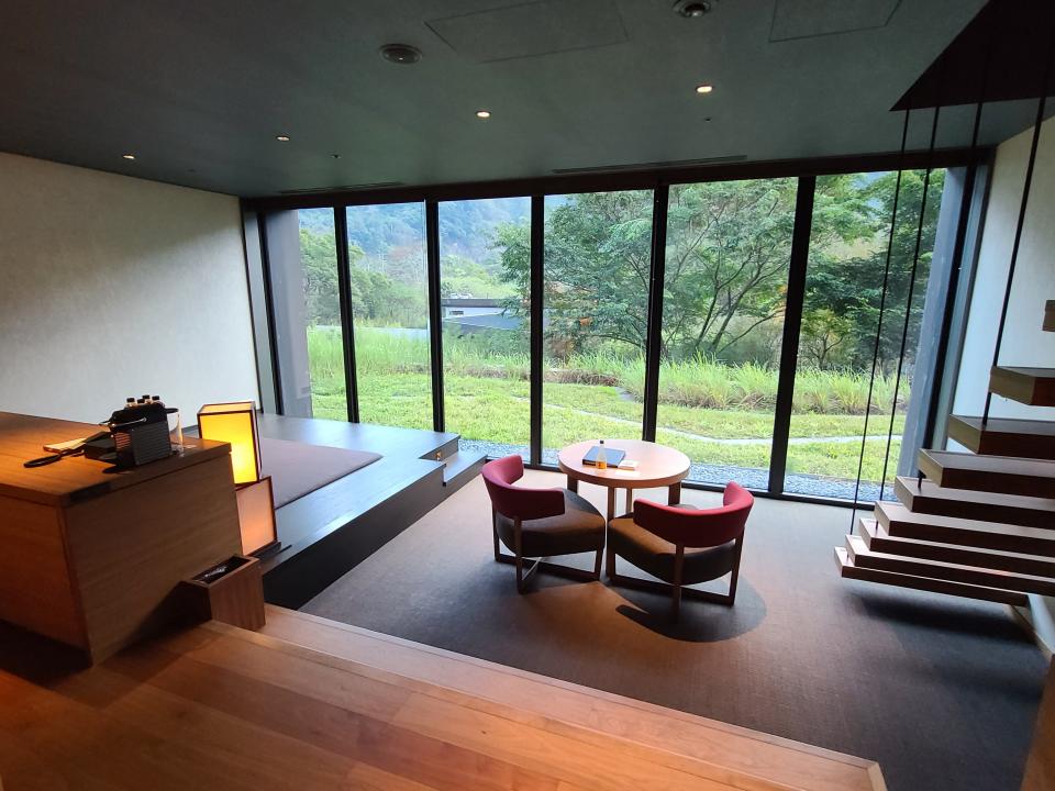 View of room in hotel with full-panel windows overlooking trees and grass