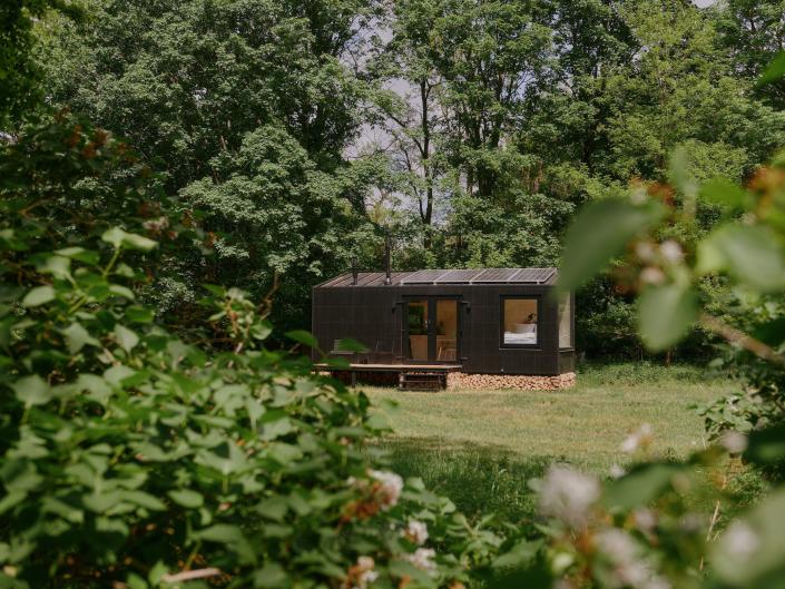 A Raus cabin outside in nature surrounded by trees