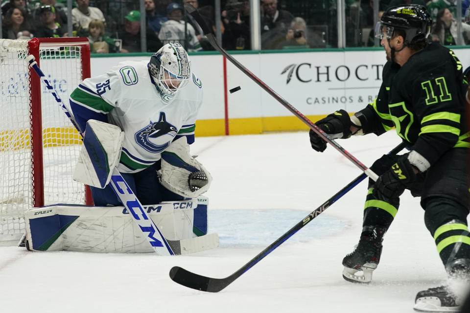 Vancouver Canucks goaltender Thatcher Demko (35) stops the puck as Dallas Stars center Luke Glendening (11) watches during the first period of an NHL hockey game in Dallas, Saturday, March 25, 2023. (AP Photo/LM Otero)