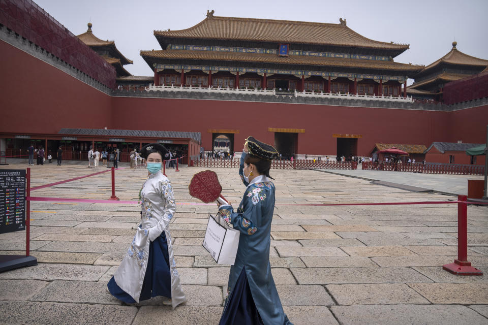 Visitors in historical dress and wearing face masks to protect against COVID-19 walk near the entrance to the Forbidden City in Beijing, Saturday, Sept. 18, 2021. (AP Photo/Mark Schiefelbein)