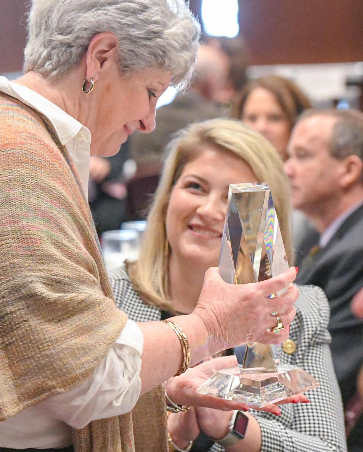 Carol Burdette, left, President and CEO of United Way of Anderson, holds the Duke Citizenship & Service Award, by Trent Acker of Duke Energy, as she comes back to the table with Liz Brock, during the 2024 Anderson Area Chamber of Commerce annual meeting at the Civic Center of Anderson, in Anderson S.C. Monday, March 4, 2024. Guest speaker U.S. Sen. Lindsey Graham spoke about community leaders, and growth in the state of South Carolina.