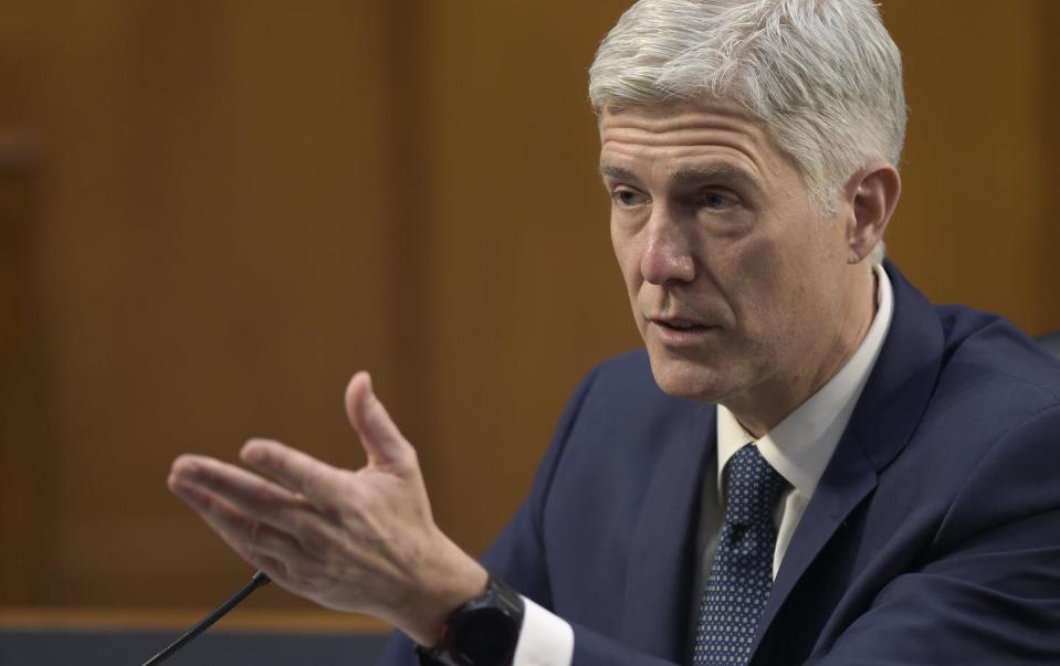 Gorsuch, seated, gestures during testimony.