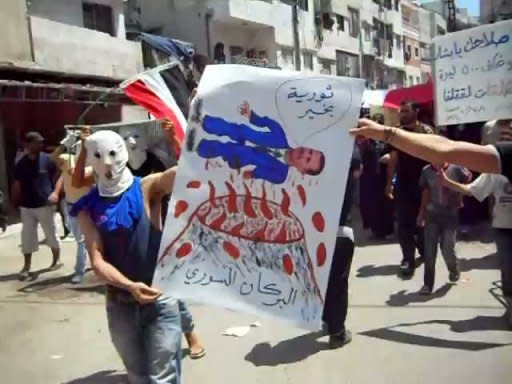 An image taken from YouTube shows Syrian anti-government protesters holding a sign which shows President Bashar Al-Assaf floating above a volcano as they march during a demonstration in the coastal city of Latakia. Syrian security forces killed six demonstrators as more than 500,000 took to the streets across the country on Friday to demand the departure of Bashar al-Assad, activists said