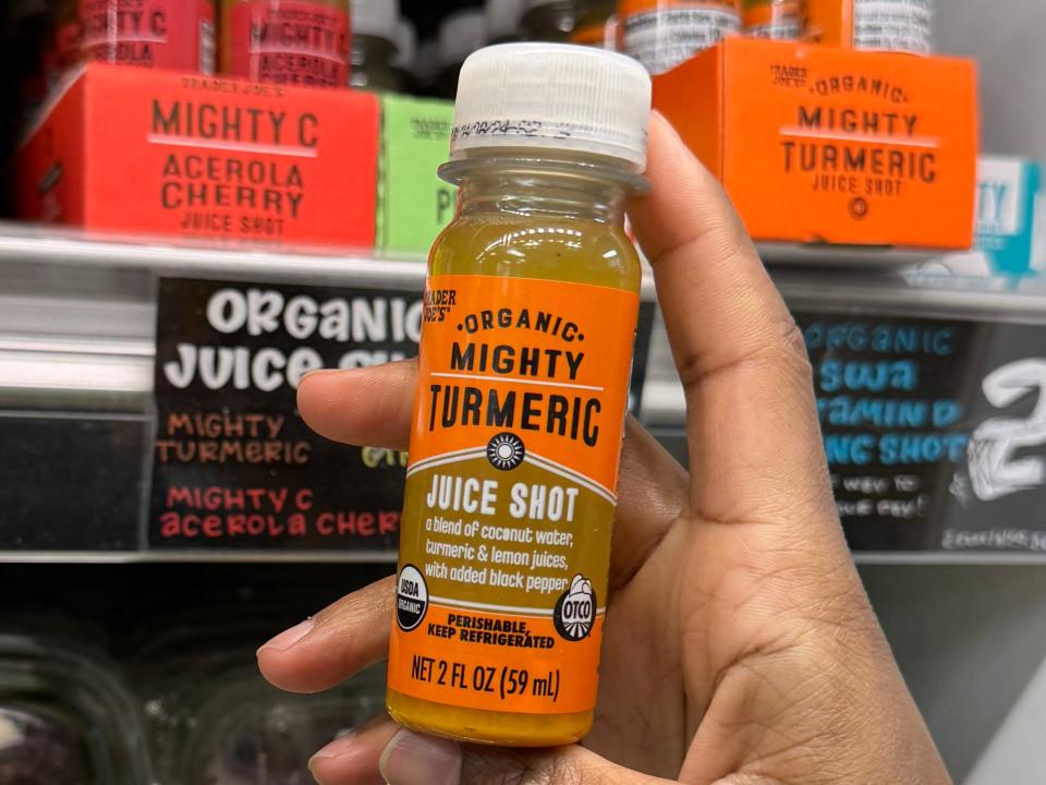 hand holding up a turmeric juice shot at trader joes