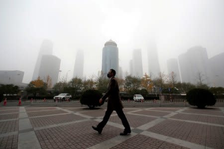 FILE PHOTO - A man wearing a mask walks in the central business district on a polluted day after a yellow alert was issued for smog, in Beijing, China November 14, 2018.  REUTERS/Jason Lee/File Photo