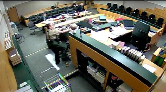 A corrections officer tries to stop the man as he lunges at a judicial assistant. Source: Facebook