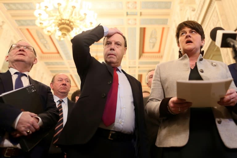 Nigel Dodds (C) and Arlene Foster (R) speak to members of the media in the Great Hall at Stormont on January 16, 2017