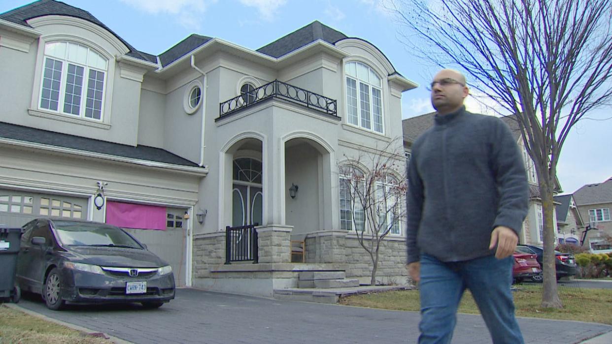 Rajan Kanwar walks past the four-bedroom house he owns on Scotchmere Crescent in Brampton. He says the tenant has paid, at best, partial rent since May, 2023.   (Tina MacKenzie/CBC - image credit)