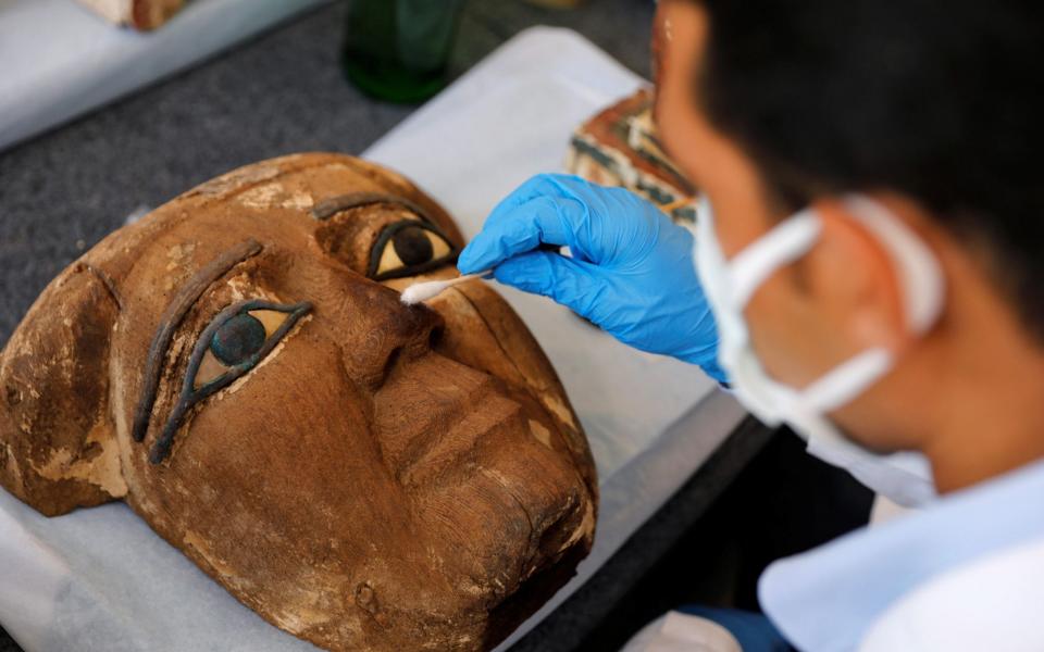 An archaeologist works on an artifact, around 2,500 years old, from the newly discovered burial site near Egypt's Saqqara necropolis - Reuters