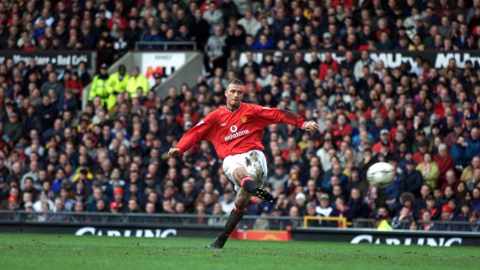 david beckham in a red soccer uniform, kicking a ball during a match