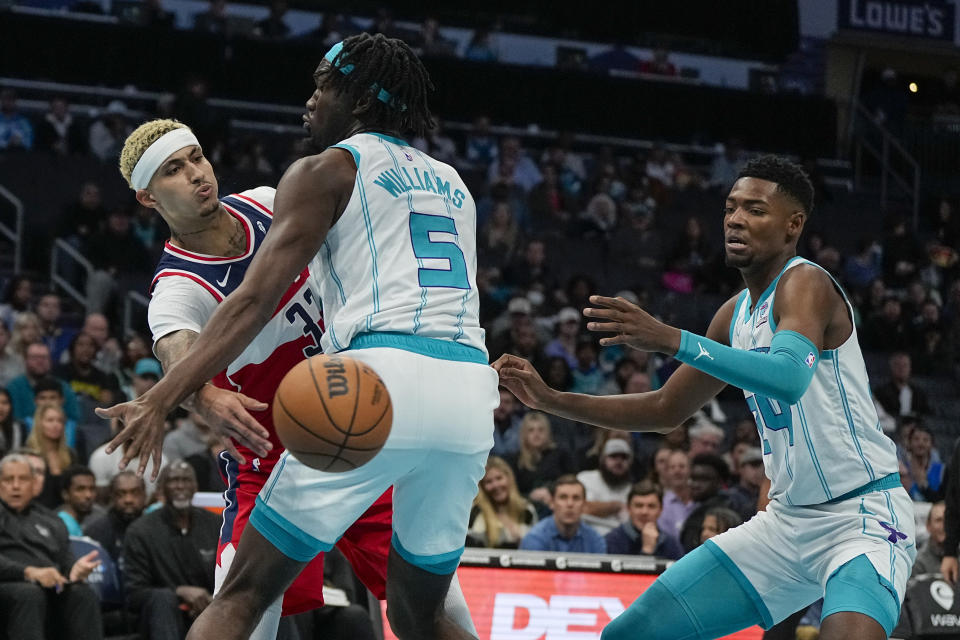Washington Wizards forward Kyle Kuzma passes around Charlotte Hornets center Mark Williams during the first half of an NBA basketball game on Wednesday, Nov. 22, 2023, in Charlotte, N.C. (AP Photo/Chris Carlson)