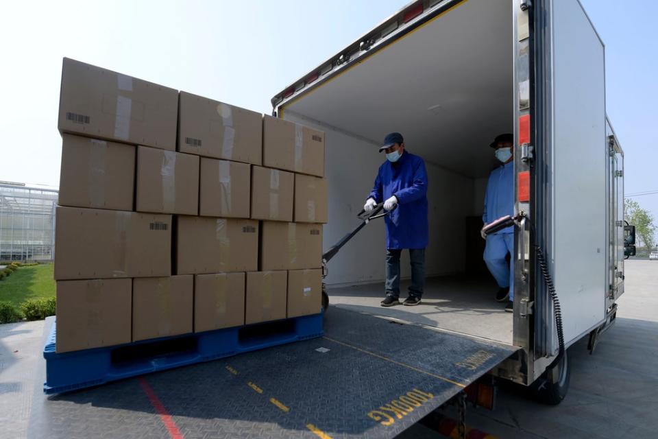 In this photo released by China’s Xinhua News Agency, workers load boxes of vegetables to be sent to urban neighborhoods at an agricultural facility in Shanghai, Tuesday, 19 April 2022 (AP)