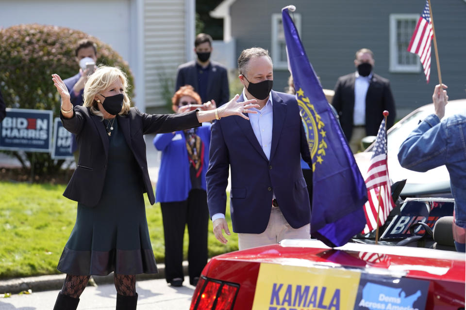 Jill Biden, left, wife of Democratic presidential candidate former vice president Joe Biden, and Doug Emhoff, center, husband of Democratic vice presidential candidate Sen. Kamala Harris, D-Calif., greet supporters in passing cars during a campaign stop, Wednesday, Sept. 16, 2020, in Manchester, N.H. (AP Photo/Steven Senne)