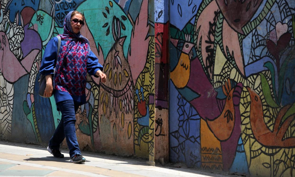 <span>An Iranian woman walks past a mural in Tehran on the eve of the second round of the presidential elections. </span><span>Photograph: Raheb Homavandi/AFP/Getty Images</span>