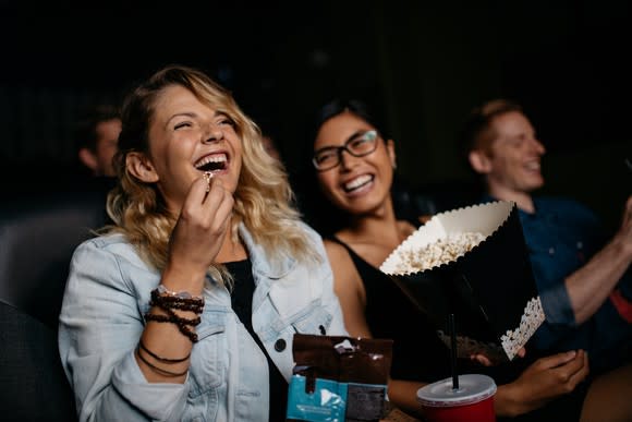 Women smiling while eating popcorn at a theater