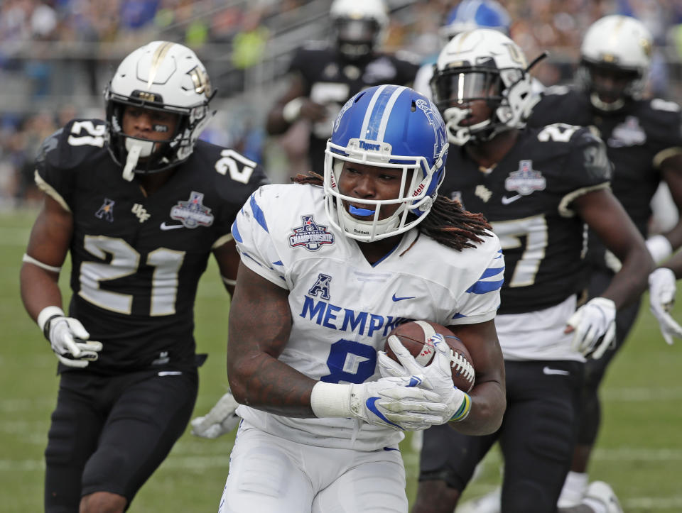 Memphis running back Darrell Henderson, center, runs past Central Florida defensive backs Rashard Causey (21) and Richie Grant, right, for a 12-yard touchdown run during the first half of the American Athletic Conference championship NCAA college football game, Saturday, Dec. 1, 2018, in Orlando, Fla. (AP Photo/John Raoux)