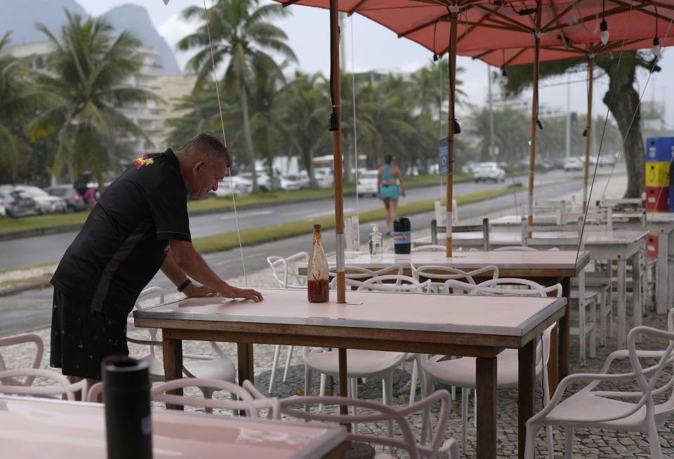 A worker at the food and bar kiosk "Nana 2" looks at the bullet hole in the table where four doctors were shot, on the beach in the Barra de Tijuca neighborhood of Rio de Janeiro, Brazil, Thursday, Oct. 5, 2023. Three of the doctors died in the overnight shooting. (AP Photo/Silvia Izquierdo)