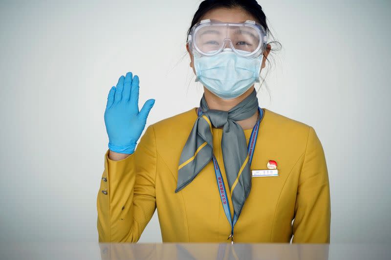 Staff member wearing face mask and goggles reacts to the camera at a counter at the Wuhan Tianhe International Airport