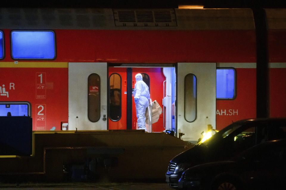 An investigator in a white protective suit works in the regional train that had been driven onto a siding in Neumunster, Germany, Wednesday, Jan. 25, 2023. Germany’s Federal Police force said the man used a knife to attack several passengers Wednesday shortly before a regional train traveling from Kiel to Hamburg arrived at the Brokstedt station. A man described as a stateless Palestinian has fatally stabbed several people and injured others on the train. (Jonas Walzberg/dpa via AP)