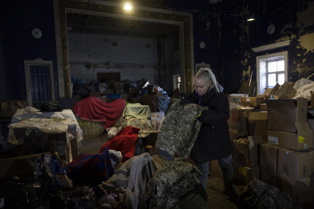 A volunteer folds army clothes inside a Ukrainian volunteer center in Mykolaiv, southern Ukraine, on Monday, March 28, 2022. Ukrainian volunteers have set up a center to supply army and civilians with clothes, food , medicines, and makeshift bullet proof vests. (AP Photo/Petros Giannakouris)