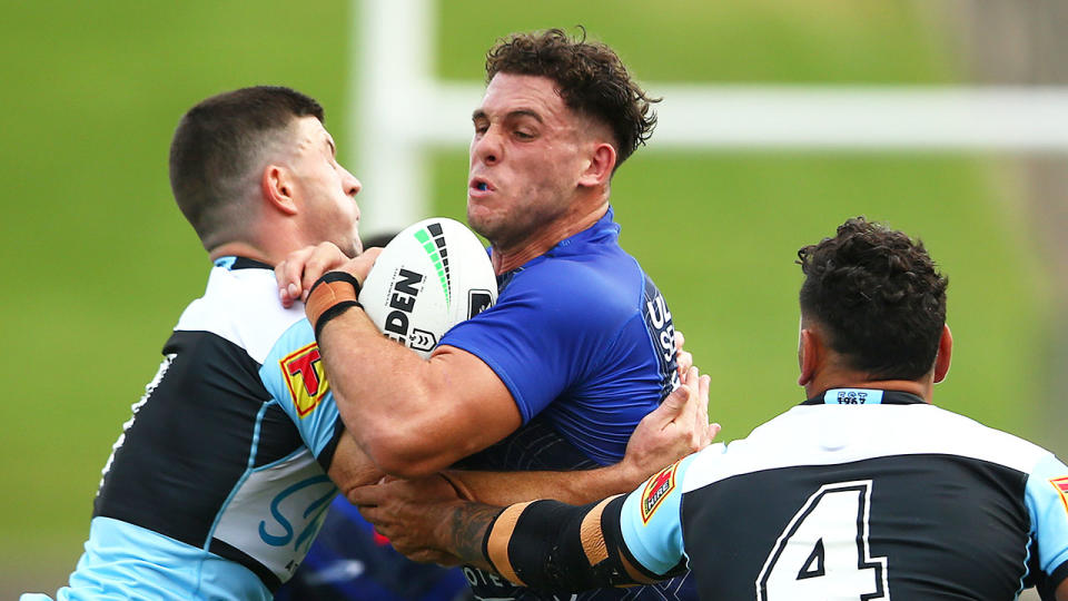 Seen here, Adam Elliott is tackled for the Bulldogs in a trial match against the Sharks. 