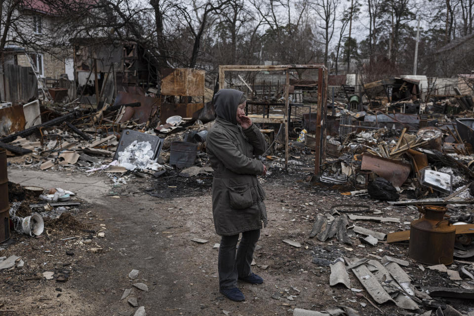 Olia, 53, hand to her mouth in dismay, looks at the devastation, with broken furniture and fragments all around her.