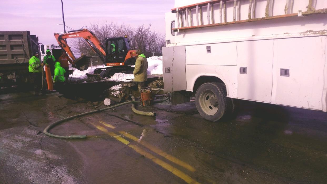 Akron city workers pump out water from a section of West Center Road in Akron near Akron Children's Hospital on Saturday.