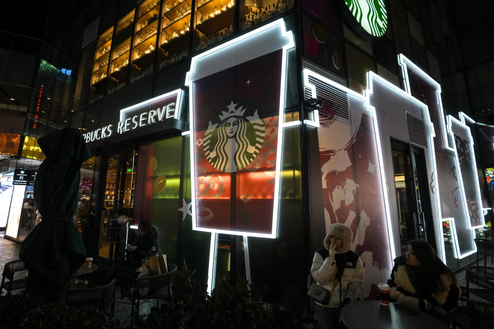 People enjoy coffee outside a Starbucks cafe at an outdoor shopping mall in Beijing on Saturday, Dec. 23, 2023. It was tumultuous 2023 for the Chinese economy. Some of the world's biggest brands said they were weighing, or already have decided, to shift manufacturing away from China amid unease about security controls, government protection of their Chinese rivals and Beijing's wobbly relations with Washington. But there was at least one bright spot for Beijing amid all the tough news about declining foreign investment: American fast food companies have announced a surge of investment in a market of 1.4 billion people. KFC, McDonald's and Starbucks are among companies in recent months that have announced plans for major investment in China. (AP Photo/Andy Wong)