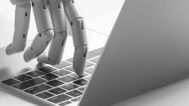 Stock image of robot hand typing on laptop