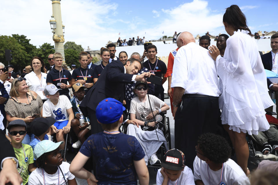 French President Emmanuel Macron makes a selfie with guests after the Bastille Day military parade Friday, July 14, 2023 in Paris. India is the guest of honor at this year's Bastille Day parade, with Prime Minister Narendra Modi in the presidential tribune alongside French President Emmanuel Macron. (AP Photo/Aurelien Morissard, Pool)