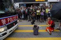 A protester sits in front of a police van to block it, in Hong Kong on Saturday, July 13, 2019. Several thousand people marched in Hong Kong on Saturday against traders from mainland China in what is fast becoming a summer of unrest in the semi-autonomous Chinese territory. (AP Photo/Kin Cheung)