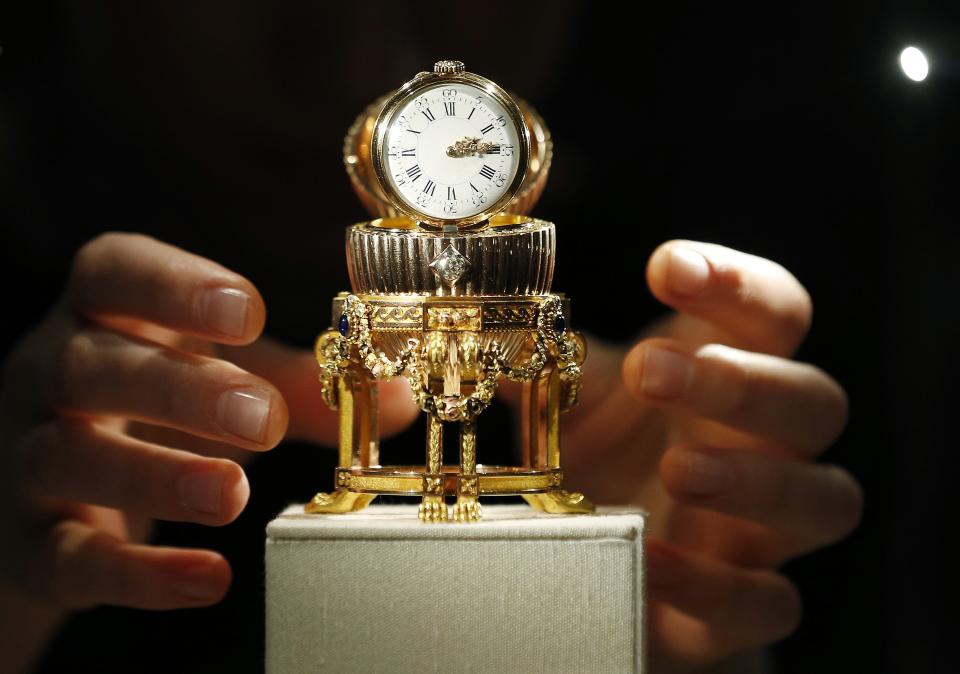 An assistant poses for a photograph with a Faberge egg during a photo-call at antique dealer Wartski, in central London