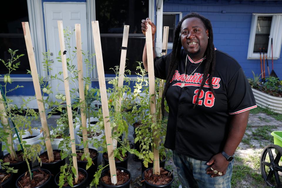 Corey "Goo" Paul wears a jersey and smiles next to a plant in his garden.