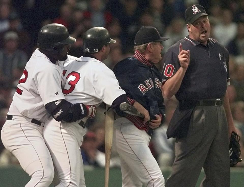 FILE - In this June 3, 1998, file photo, Boston Red Sox manager Jimy Williams, second from right, gets between home plate umpire Tim Welke, right, and batter John Valentin, while teammate Mo Vaugh restrains Valentin, who was arguing two called strikes from Baltimore Orioles pitcher Doug Johns in the fourth inning of a baseball game at Fenway Park in Boston. Valentin and Williams were ejected from the game. Automatic balls and strikes could soon be coming to the major leagues. Disappearing with that are the complaints that an umpire’s strike zone was too wide or a pitcher was getting squeezed, followed by the helmet-slamming, dirt-kicking dustups that are practically as old as the sport itself. (AP Photo/Charles Krupa, File)