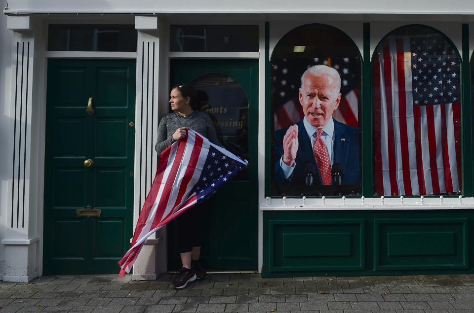 BALLINA, IRELAND - NOVEMBER 07: on November 7, 2020 Catherine Hallahan stands with an American flag outside her fatherâs barber shop as Ballina locals celebrate in anticipation of Joe Biden being elected as the next US President in Ballina, Ireland. Joe Biden whose distant relatives hail from the County Mayo town of Ballina has visited the town twice before as the former Vice President. The US election count continues with Biden favoured to win. Photo: Charles McQuillan/Getty Images