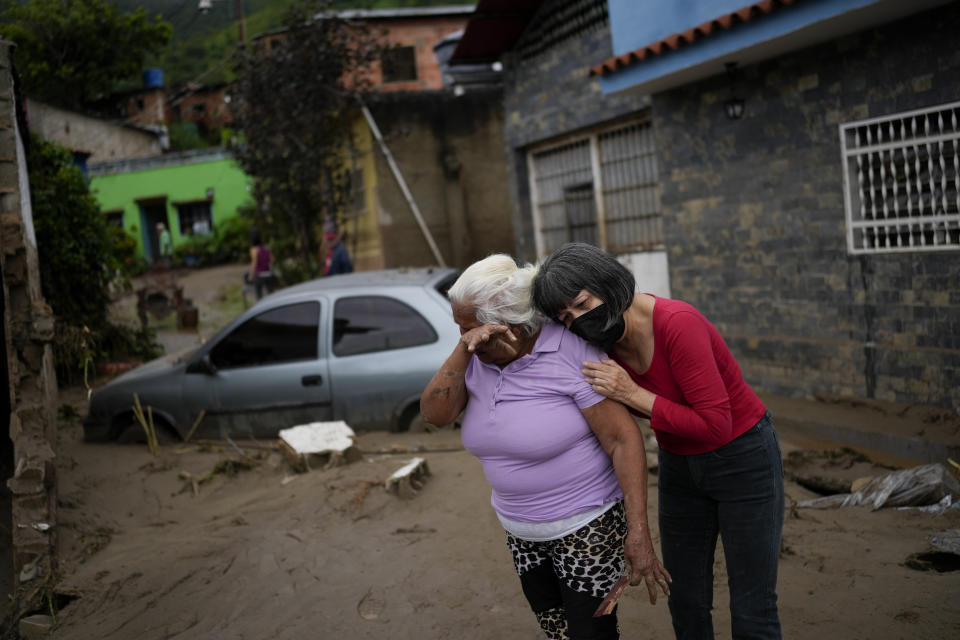 Women embrace in a flooded street outside their home in Las Tejerias, Venezuela, Sunday, Oct. 9, 2022. Days of heavy rain caused flash floods and overflowed Las Tejerias River. (AP Photo/Matias Delacroix)
