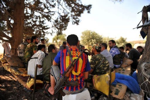 An armed Syrian rebel wearing the jersey of FC Barcelona rests with comrades near the northern city of Aleppo. Feared forces led by President Bashar al-Assad's brother used helicopter gunships Sunday in a new assault on rebels in Damascus, activists said, as clashes also raged in Syria's second city Aleppo