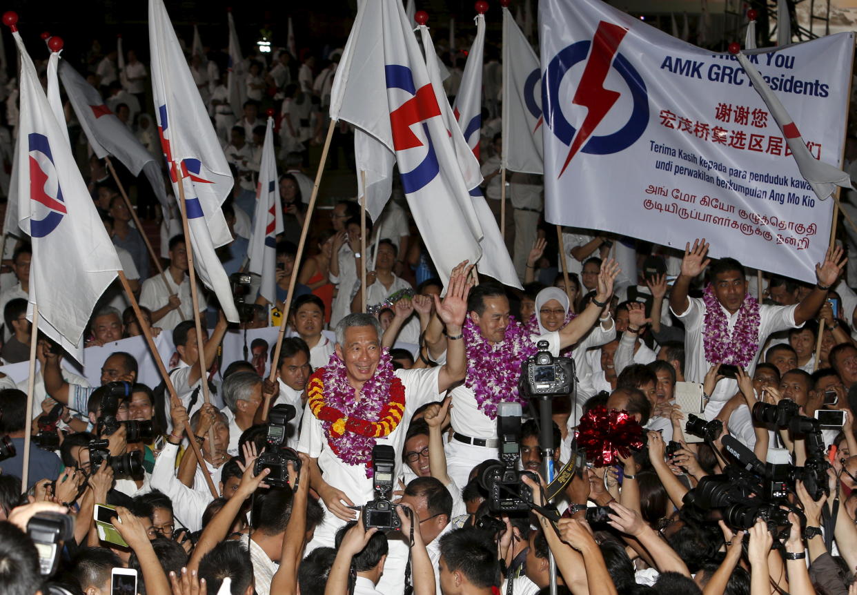 Singapore's Prime Minister and Secretary-General of the People's Action Party Lee Hsien Loong (C) celebrates with supporters after the general election results at a stadium in Singapore September 12, 2015.  Singapore voted on Friday in its most hotly contested general election with the outcome expected to test the long-ruling People's Action Party's (PAP) dominance of politics even though it is bound to win. REUTERS/Edgar Su 