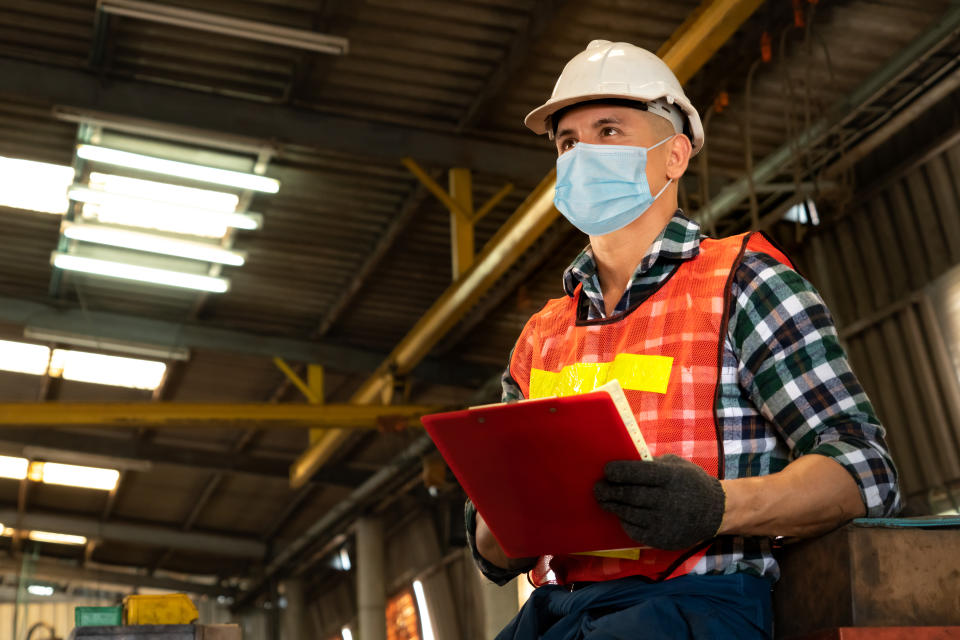 Factory workers with face mask protect from outbreak of Coronavirus Disease 2019 or COVID-19. Concept of protective action and quarantine to stop spreading of Coronavirus Disease 2019 or COVID-19.