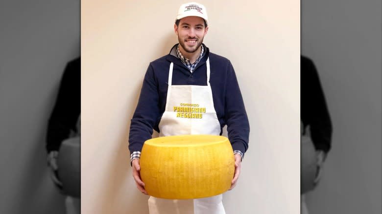 man holding wheel of cheese
