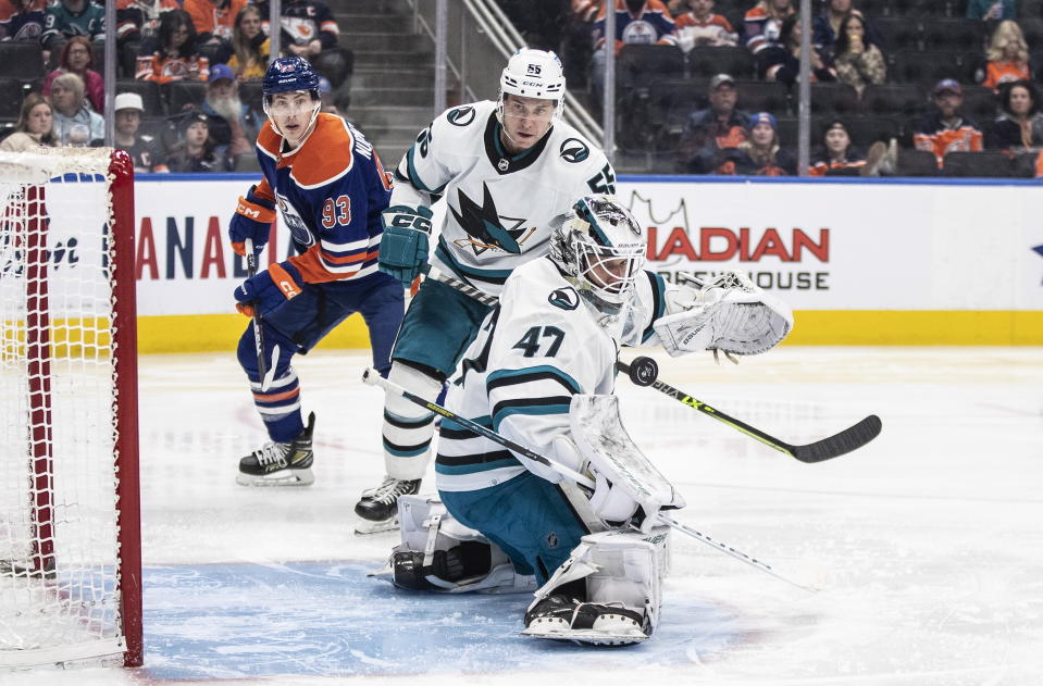 San Jose Sharks goalie James Reimer (47) makes a save as Sharks' Dylan Holloway (55) and Edmonton Oilers' Ryan Nugent-Hopkins (93) look for a rebound during second-period NHL hockey game action in Edmonton, Alberta, Monday, March 20, 2023. (Jason Franson/The Canadian Press via AP)