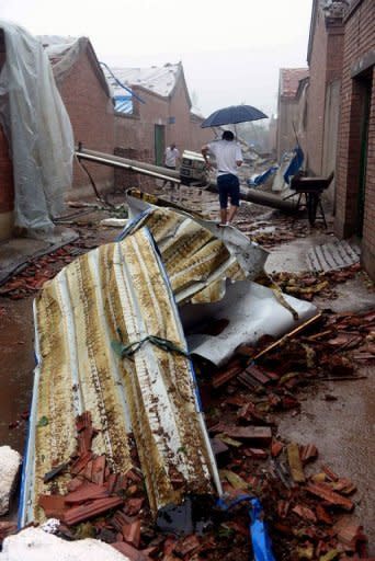 Residents making their way home through debris as a storm hits in Beijing. The death toll from the heaviest rain to hit Beijing in over 60 years has risen to 37, Chinese state media reported on Sunday