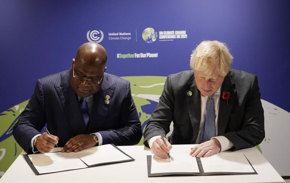 British Prime Minister Boris Johnson, right, signs a book with Democratic Republic of Congo's President and African Union Chair Felix Tshisekedi on the sidelines of the COP26 U.N. Climate Summit in Glasgow, Scotland, Tuesday, Nov. 2, 2021. The U.N. climate summit in Glasgow gathers leaders from around the world, in Scotland's biggest city, to lay out their vision for addressing the common challenge of global warming. (AP Photo/Alberto Pezzali, Pool)