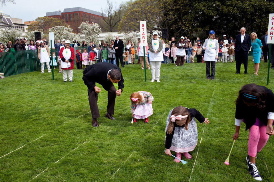 Obama cheers on a young child as she rolls her egg toward the finish line April 13, 2009, during the White House Easter Egg Roll.