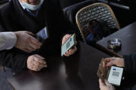 A waiter checks clients' vaccine pass in a restaurant, in Paris, Monday, Jan. 24, 2022. Unvaccinated people are no longer allowed in France's restaurants, bars, tourist sites and sports venues. A new law came into effect Monday requiring a "vaccine pass" that is central to the government's anti-virus strategy. (AP Photo/Thibault Camus)