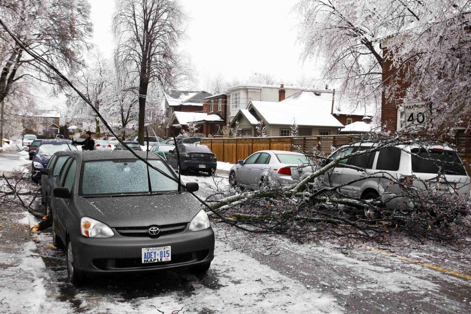 A downed powerline runs over a parked vehicle after ice-covered tree branches came down following freezing rain in Toronto